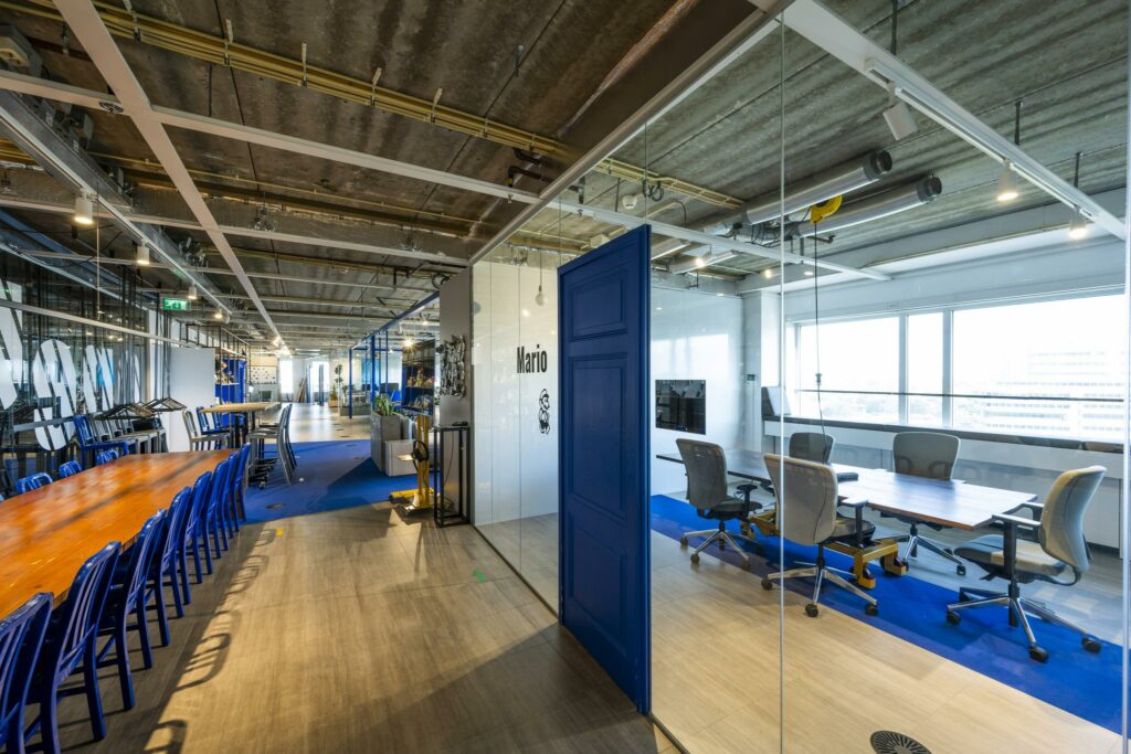 Moderne kantoorruimte aan de Johan Huizingalaan met glazen vergaderruimte genaamd "Mario", ingericht met vergadertafel en bureaustoelen.